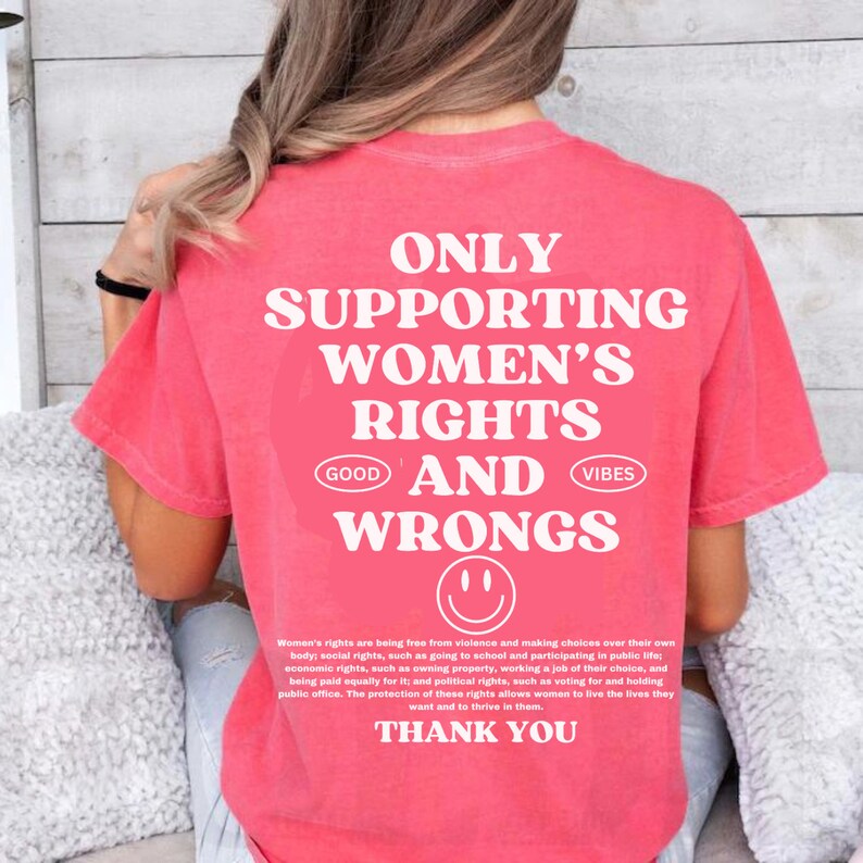 May include: Pink t-shirt with white text that reads "Only Supporting Women's Rights Good and Wrongs" with a smiley face below the text. The text continues with a description of women's rights and ends with "Thank You".