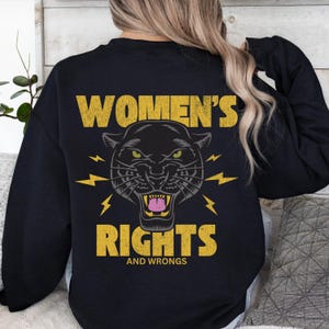 May include: Black sweatshirt with a yellow graphic of a black panther with lightning bolts and the text "Women's Rights and Wrongs".