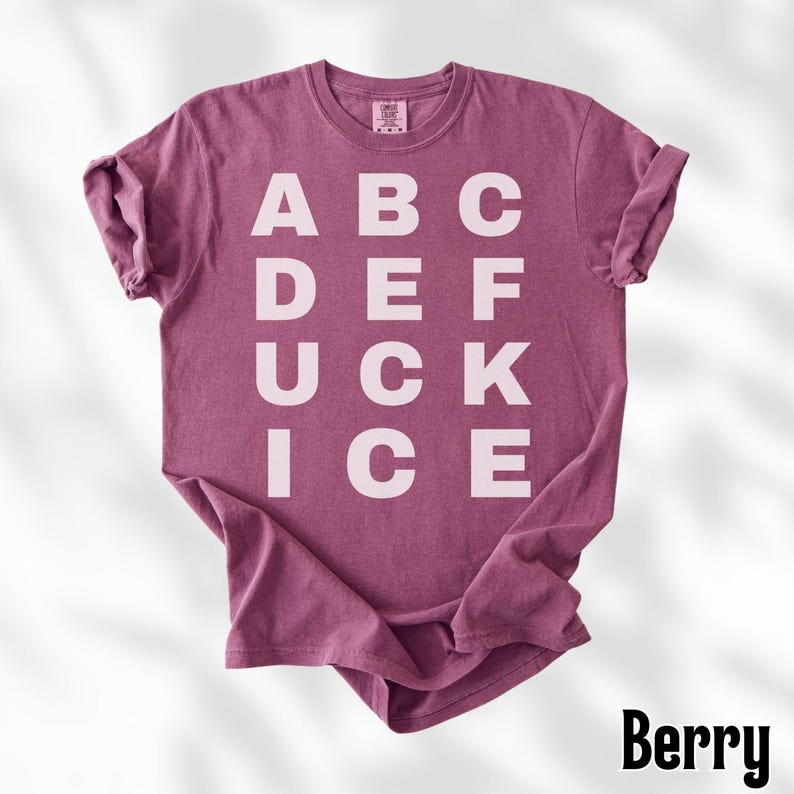 May include: Berry-colored t-shirt with the letters ABC, DEF, UCK, and ICE printed in white. The shirt has a crew neck and short sleeves. The word "Berry" is printed in a black, stylized font at the bottom right corner.