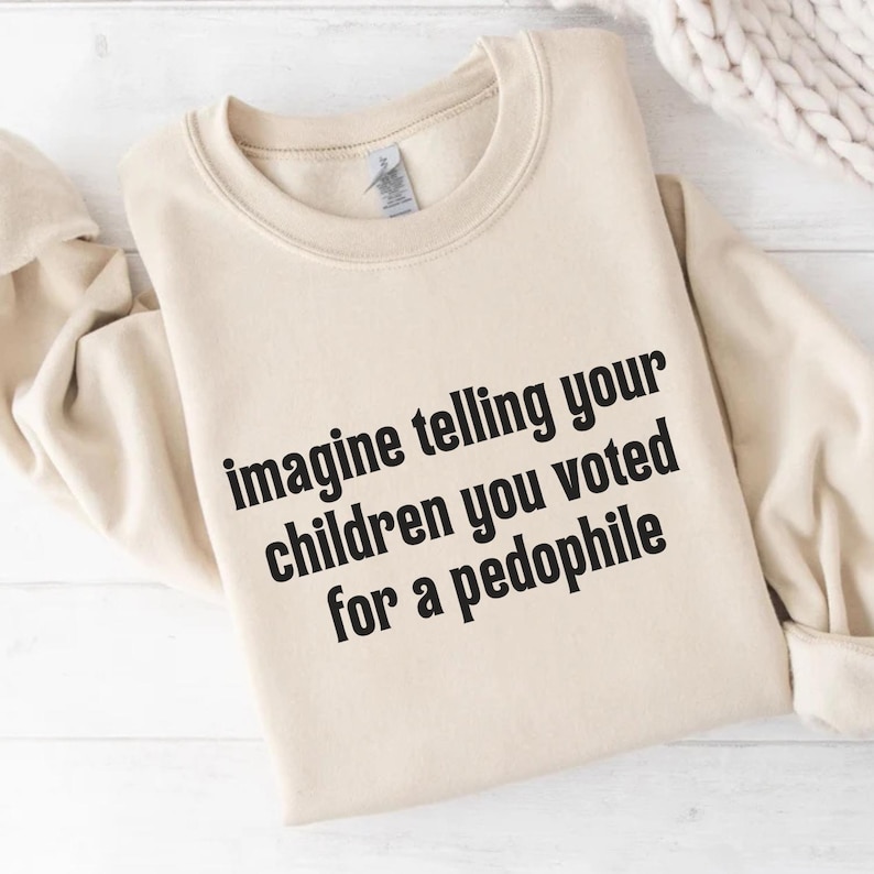 May include: A beige crewneck sweatshirt with the text "imagine telling your children you voted for a pedophile" in black. The sweatshirt is folded and displayed on a white surface.
