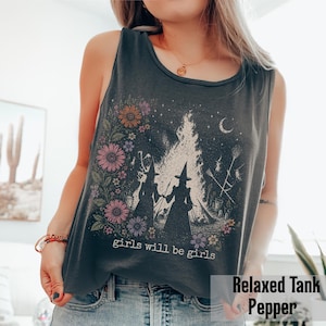 May include: A dark gray relaxed tank top with a floral and witch-themed graphic. The design features two witch silhouettes, a bonfire, flowers, and the text "girls will be girls". The tank top is a pepper color.