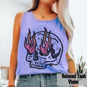 May include: A violet Relaxed Tank top with a graphic skull design. The skull has flames for eyes, with pink and orange accents. The text "Relaxed Tank Violet" is printed at the bottom of the image.