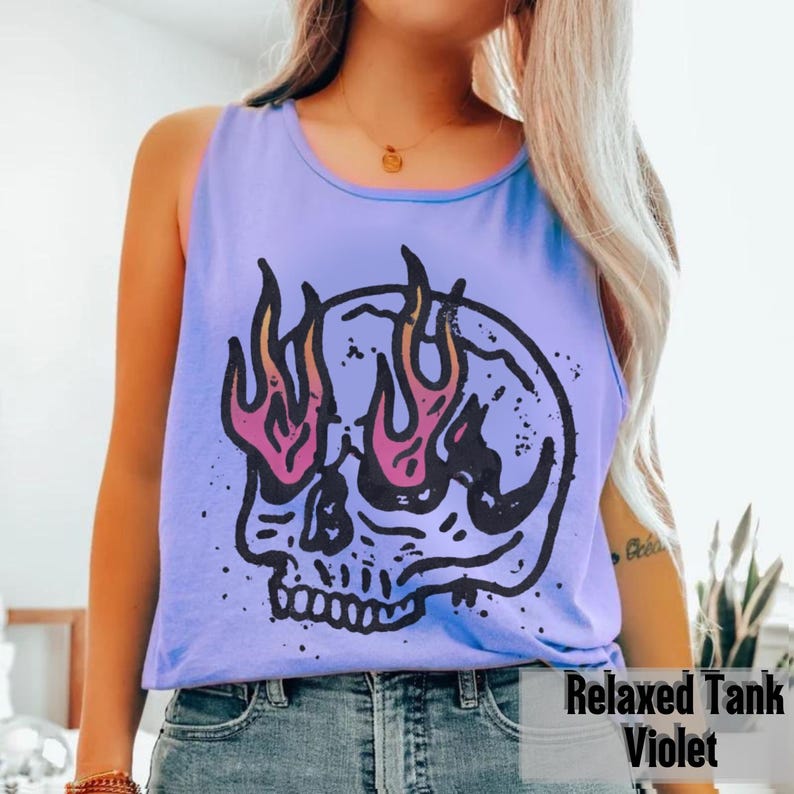 May include: A violet Relaxed Tank top with a graphic skull design. The skull has flames for eyes, with pink and orange accents. The text "Relaxed Tank Violet" is printed at the bottom of the image.