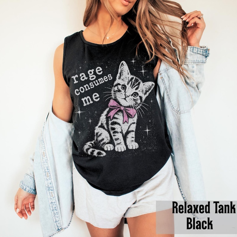 May include: A black sleeveless tank top featuring a graphic of a grey tabby kitten wearing a pink bow. The text "rage consumes me" is printed in white above the kitten, surrounded by small white star accents on the front of the garment.