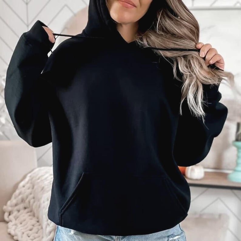 May include: A solid black hoodie with a front pocket and a drawstring hood. The hoodie is made of a soft material and is a casual style. The sleeves have ribbed cuffs. The hoodie is a versatile piece of clothing.