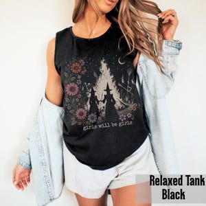 May include: Black relaxed tank top with a floral and witch graphic. The graphic features two witch silhouettes, flowers, and the text "girls will be girls". The tank top is sleeveless.