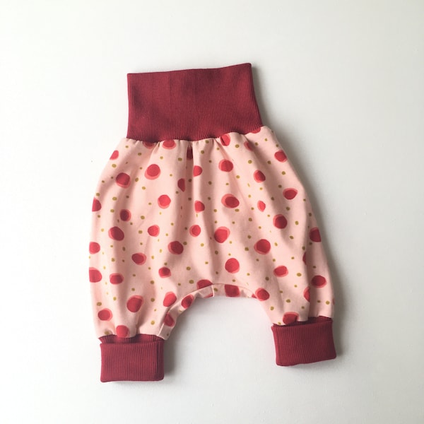 Pantalon rose boule à pois rouges. Coton. Pantalon large confortable pour bébé. Sarouel. Taille et poignets rabattables rouges. Pantalon fille