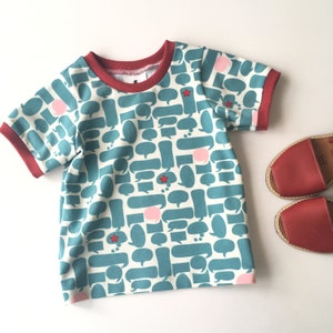 T-shirt met tekst ballonnen. Kinder truitje, babyshirt. Kindershirt met blauwe tekst ballonnen. Shirtje met korte mouwen.