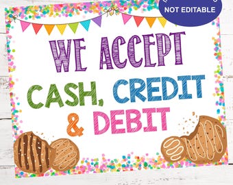 May include: A colorful printable sign with confetti and flags that reads "We Accept Cash, Credit & Debit". The sign also features a broken cookie and a whole cookie.