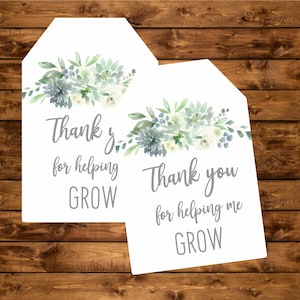 May include: Two white gift tags with a watercolor floral design in shades of green and blue. The text on the tags reads "Thank y for helping GROW" and "Thank you for helping me GROW".
