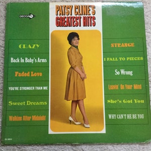 May include: Vintage Patsy Cline's Greatest Hits album cover. The album features a photo of Patsy Cline in a mustard-colored dress. The album cover has a green background with song titles like "Crazy" and "I Fall to Pieces".