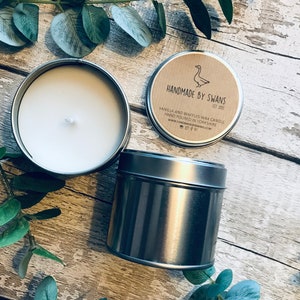 May include: A silver tin candle with a brown paper label that reads "Handmade by Swans Est 2015" and "Vanilla and Waffles Wax Candle Hand Poured in Yorkshire www.handmadebyswans.com".