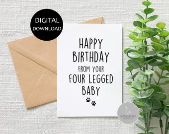Puede incluir: Una tarjeta blanca con texto negro que dice "Feliz cumpleaños de tu bebé de cuatro patas" con dos huellas de patas en la parte inferior. La tarjeta está sobre un sobre marrón y una planta verde.