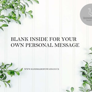 May include: White background with green leafy branches on either side. The text "BLANK INSIDE FOR YOUR OWN PERSONAL MESSAGE" is in the center of the image. Below the text is the website address "www.handmadebyswans.co.uk". In the upper right corner is a gray circle with a white outline and a white line drawing of a goose. The text "HANDMADE BY SWANS HOMEWARES & GIFTS" is inside the circle.