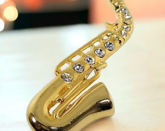 Vintage guldfärgad saxofonbrosch med klara strass-nålar