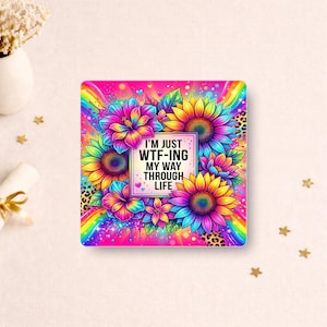 May include: A square coaster featuring a vibrant rainbow background with leopard print accents and colourful sunflowers. A central white square contains the black text: I'M JUST WTF-ING MY WAY THROUGH LIFE. The design includes bright pink, blue, and yellow hues.