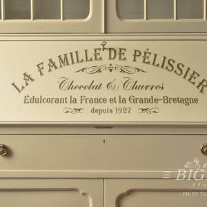 May include: A white painted wooden cabinet with a sign that reads "La Famille de Pelissier Chocolat & Churros &Eacute;dulcorant la France et la Grande-Bretagne depuis 1927".