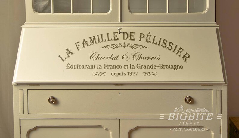 May include: A white painted wooden cabinet with a sign that reads "La Famille de Pelissier Chocolat & Churros &Eacute;dulcorant la France et la Grande-Bretagne depuis 1927".