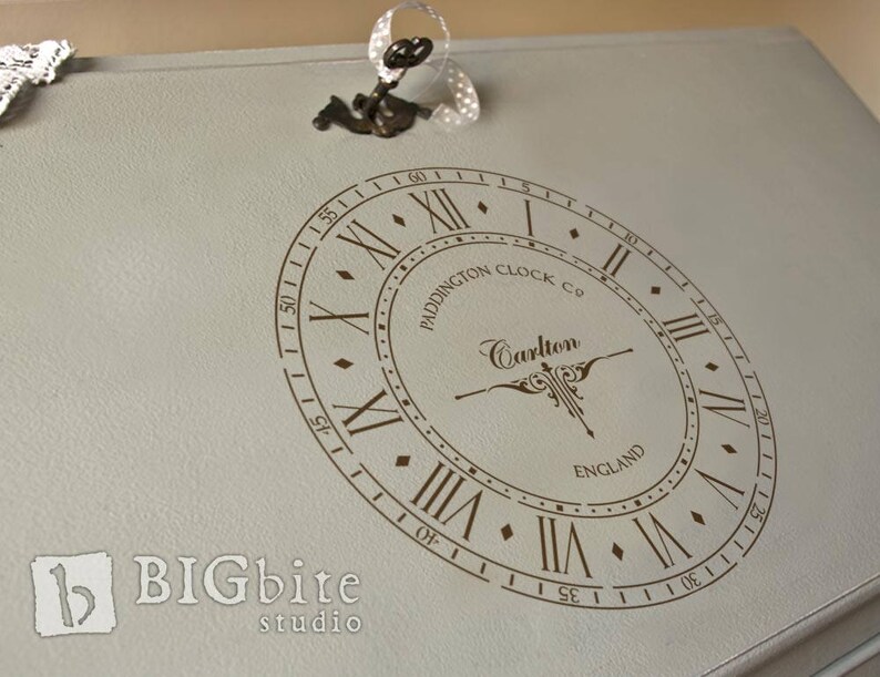 May include: A vintage-style clock face with Roman numerals and the text "Paddington Clock Co. Carlton England" in a brown font on a light gray background.