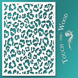 Puede incluir: Plantilla blanca con un diseño de estampado de leopardo. La plantilla es rectangular y tiene una superficie lisa. El texto "TOUCH THE WOOD" está impreso en el lado derecho de la plantilla.