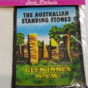 May include: Cloth badge featuring an image of The Australian Standing Stones in Glen Innes, N.S.W. The patch has a black border and a blue, pink, and white header that reads "Cloth Badge" and "Made in Australia".
