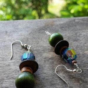 May include: A pair of green and blue earrings with wooden beads and iridescent glass beads.