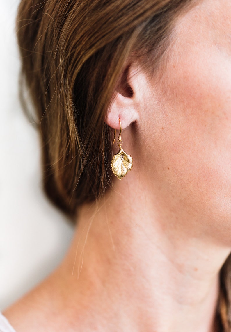 Pu&ograve; includere: Orecchini a foglia d'oro con un design delicato e dettagliato. Gli orecchini sono di stile pendente e hanno una chiusura a gancio.