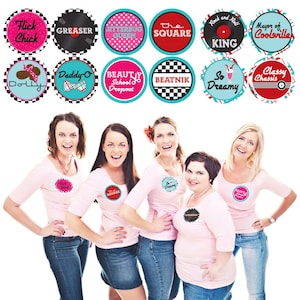 May include: Five women wearing pink t-shirts with different 1950s themed badges. The badges feature phrases like "Flick Chick", "Greaser", "Jitterbug Queen", "The Square", "Rock and Roll King", "Mayor of Coolsville", "Daddy-O", "Beauty School Dropout", "Beatnik", "So Dreamy", "Classy Chassis", and "Dolly".
