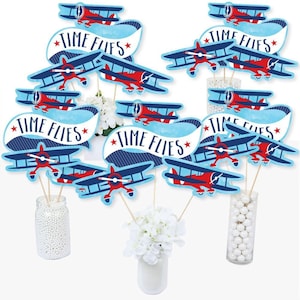 May include: Blue and red airplane themed party decorations with the text "Time Flies" on banners. The decorations are on sticks and can be used as centerpieces.