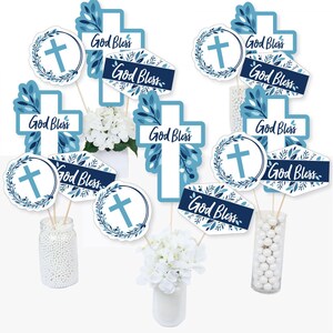 May include: Blue and white cross and wreath centerpieces with the text "God Bless" for a baptism or christening party.