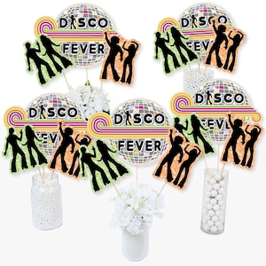 May include: Six colorful disco fever themed centerpieces with a silver glitter disco ball, rainbow stripes, and black silhouettes of dancers. The centerpieces are perfect for a 70s themed party.