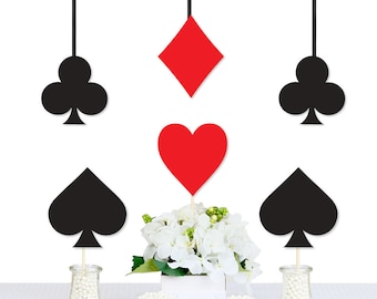 May include: Black and red card suit centerpieces for a party or event. The centerpieces feature a heart, diamond, and spade card suits. The centerpieces are hanging from the ceiling and are made of cardboard.