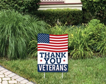 May include: A red, white, and blue American flag with the words "Thank You Veterans" printed on a blue background. The flag is on a yard sign.