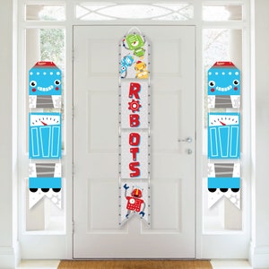 May include: A set of three robot-themed door banners for a party. The banners are made of cardboard and feature colorful robots and the word "ROBOTS" in red letters. The banners are hung on a white door.