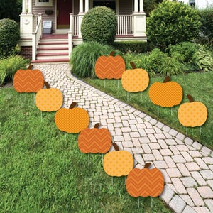 May include: A set of ten orange and brown pumpkin yard signs with different patterns. The signs are arranged in a line on a grassy lawn.