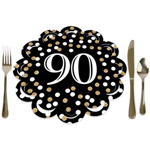 May include: Black and gold 90th birthday party table setting with white polka dots. The table setting is a paper plate with a scalloped edge.