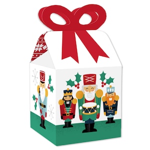 May include: Set of four Christmas-themed favor boxes featuring a Nutcracker theme. The boxes are white with a red bow on top and a green base. The front of the boxes feature a Nutcracker design with three Nutcrackers playing instruments. The boxes are perfect for holding small gifts or treats.