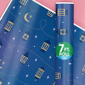 May include: Blue wrapping paper with a gold glitter pattern of crescent moons and lanterns. The paper is rolled up and has a label that says "7 ft. Roll Made in the USA".