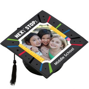 May include: A black graduation cap with a photo of three smiling girls. The cap has colorful accents, a pencil and ruler design, and the text "NEXT STOP: Middle School."
