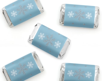 May include: Five rectangular chocolate bars wrapped in silver foil with light blue paper labels. Each label features a central silver glitter snowflake flanked by two smaller white snowflakes, accented with small silver glitter dots.