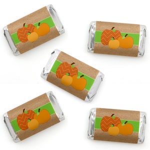 May include: Five rectangular chocolate bars wrapped in silver foil with paper labels featuring a brown kraft paper background, a horizontal lime green stripe, and three orange pumpkins with chevron, grid, and solid patterns.