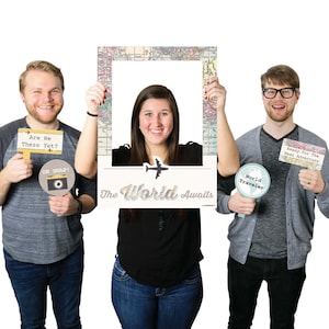 May include: A photo booth prop set with a large frame featuring a vintage world map design. The frame has a cutout for a face and the text "The World Awaits". The set includes three props: a sign that says "Are We There Yet?", a sign that says "World Traveler", and a sign that says "Ready For The Next Adventure".