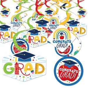 May include: A set of graduation party decorations featuring colorful swirl decorations with graduation caps, pencils, rulers, and apples. The decorations have the text "Congrats Grad!" on them.