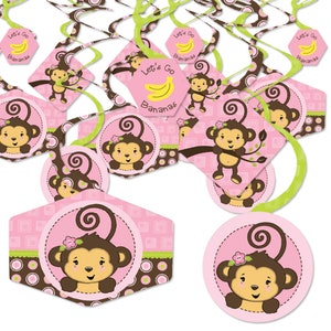 May include: Pink, brown, and green monkey-themed party decorations. The decorations include hanging swirls and cutouts with monkey illustrations, flowers, and the text "Let's Go Bananas".