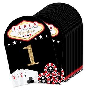 May include: Black and gold table number cards with a Las Vegas casino theme. The cards feature a red and white poker chip design, playing cards, and a gold glitter number. The text "Table Number" is displayed in a red and gold sign.