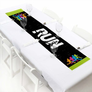 May include: Black and green table runner with the word "RUN" in white and colorful silhouettes of runners.