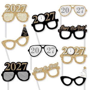 May include: A set of ten New Year's Eve photo booth props featuring various eyeglass designs. The props include gold glitter, black, and white colors with the text 2027, Happy New Year, and clock faces. Each prop is attached to a thin white stick.