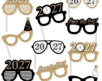 May include: A set of ten New Year's Eve photo booth props featuring various eyeglass designs. The props include gold glitter, black, and white colors with the text 2027, Happy New Year, and clock faces. Each prop is attached to a thin white stick.
