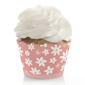 May include: Pink cupcake liner with a white daisy pattern. The liner is decorated with white frosting.