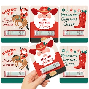 Pode incluir: Seis cartões de presente com tema natalino em vermelho e verde. Os cartões apresentam um Papai Noel de desenho animado usando um chapéu de cowboy e o texto "Giddy Up", "Jingle Horse", "Ho Ho Howdy" e "Wrangling Christmas Cheer".